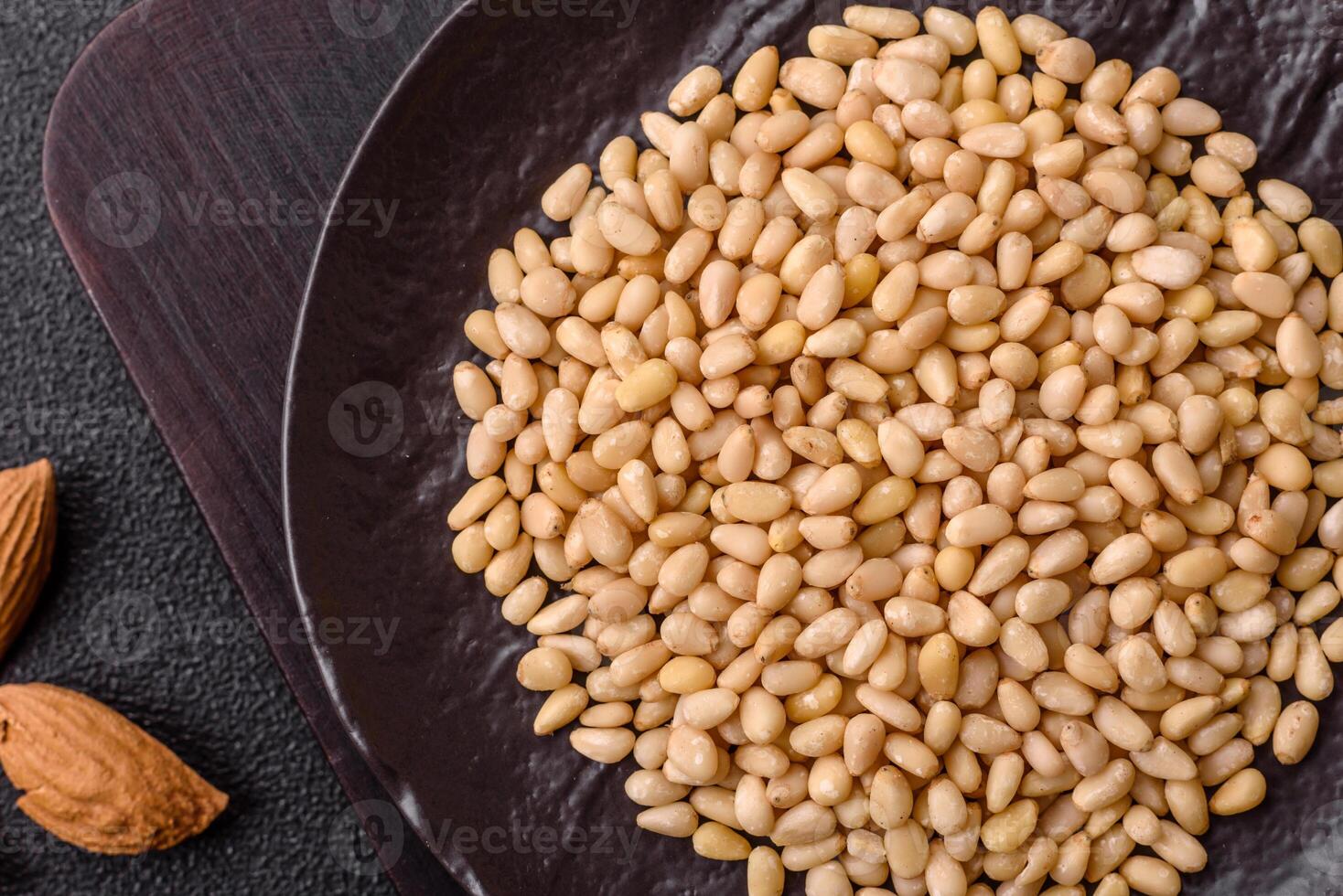 Peeled pine nuts in a bowl on a concrete background photo