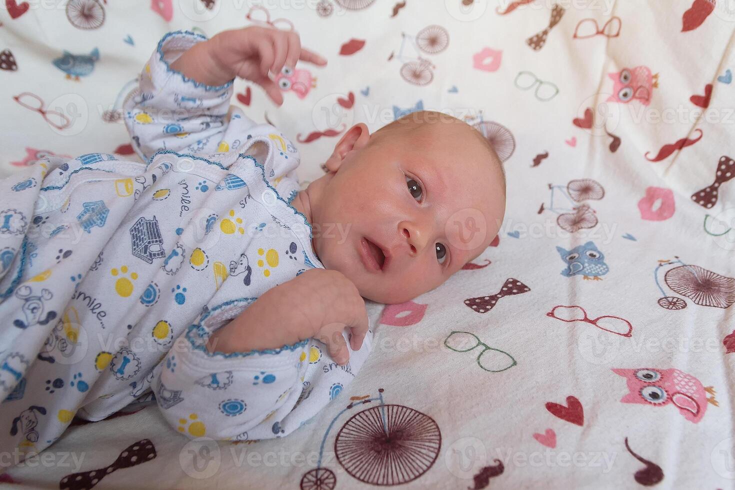 A charming newborn child a pain with open eyes lying on a comfortable bed photo