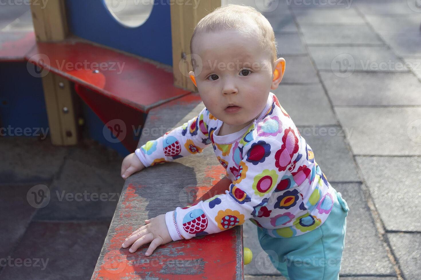 The baby plays on the playground in the park on a sunny day photo