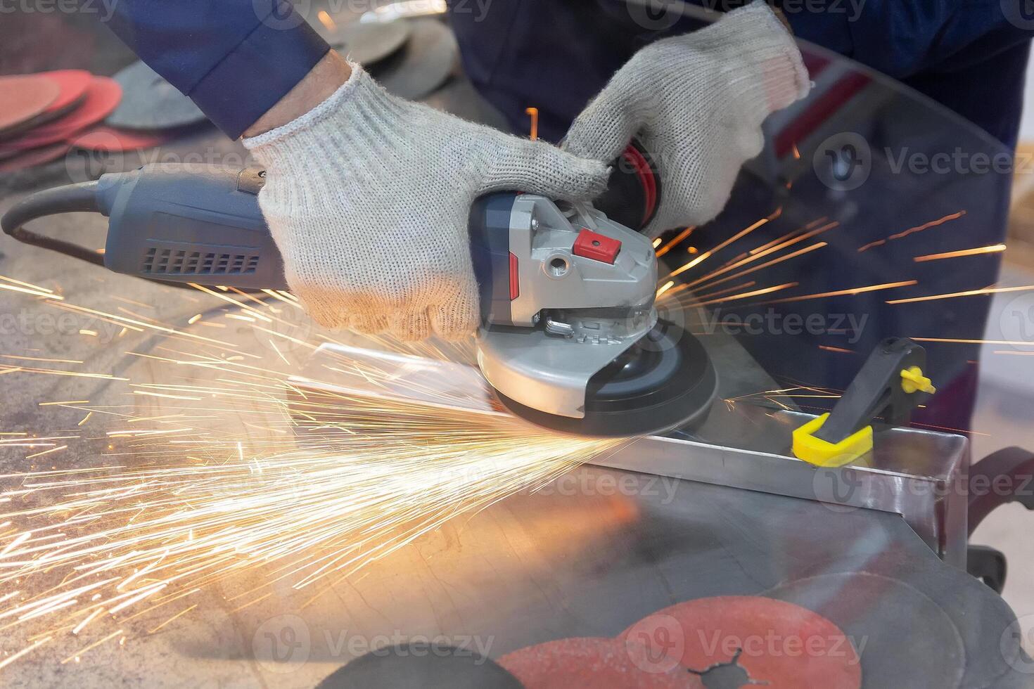 Mechanic using angle grinder and working with metal in workshop photo