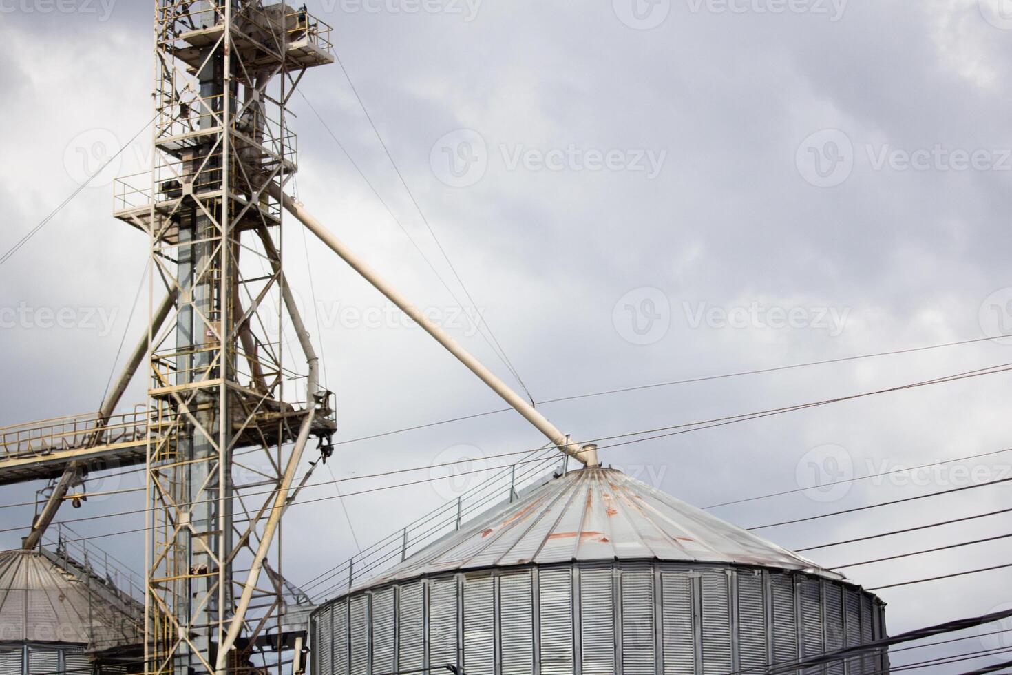 metal grain silos with industrial piping and cloudy sky, ideal for agriculture, storage, and industrial infrastructure concepts photo