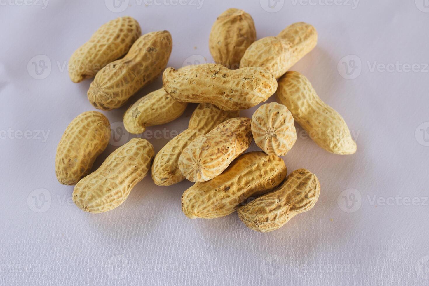 Natural unshelled peanuts displayed on plain white food background photo