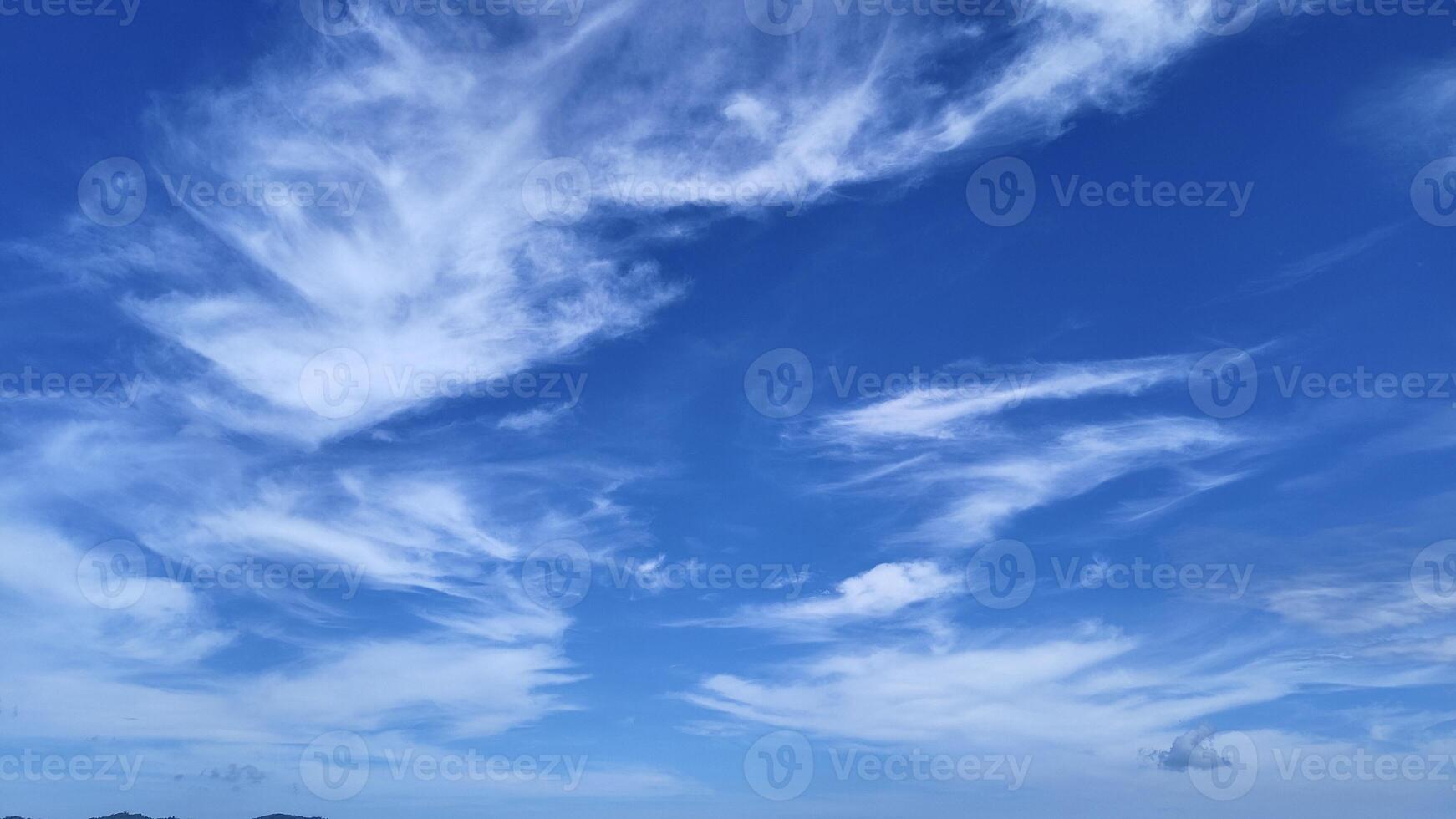 Bright Blue Sky with Soft White Clouds Floating Peacefully Over the Horizon photo