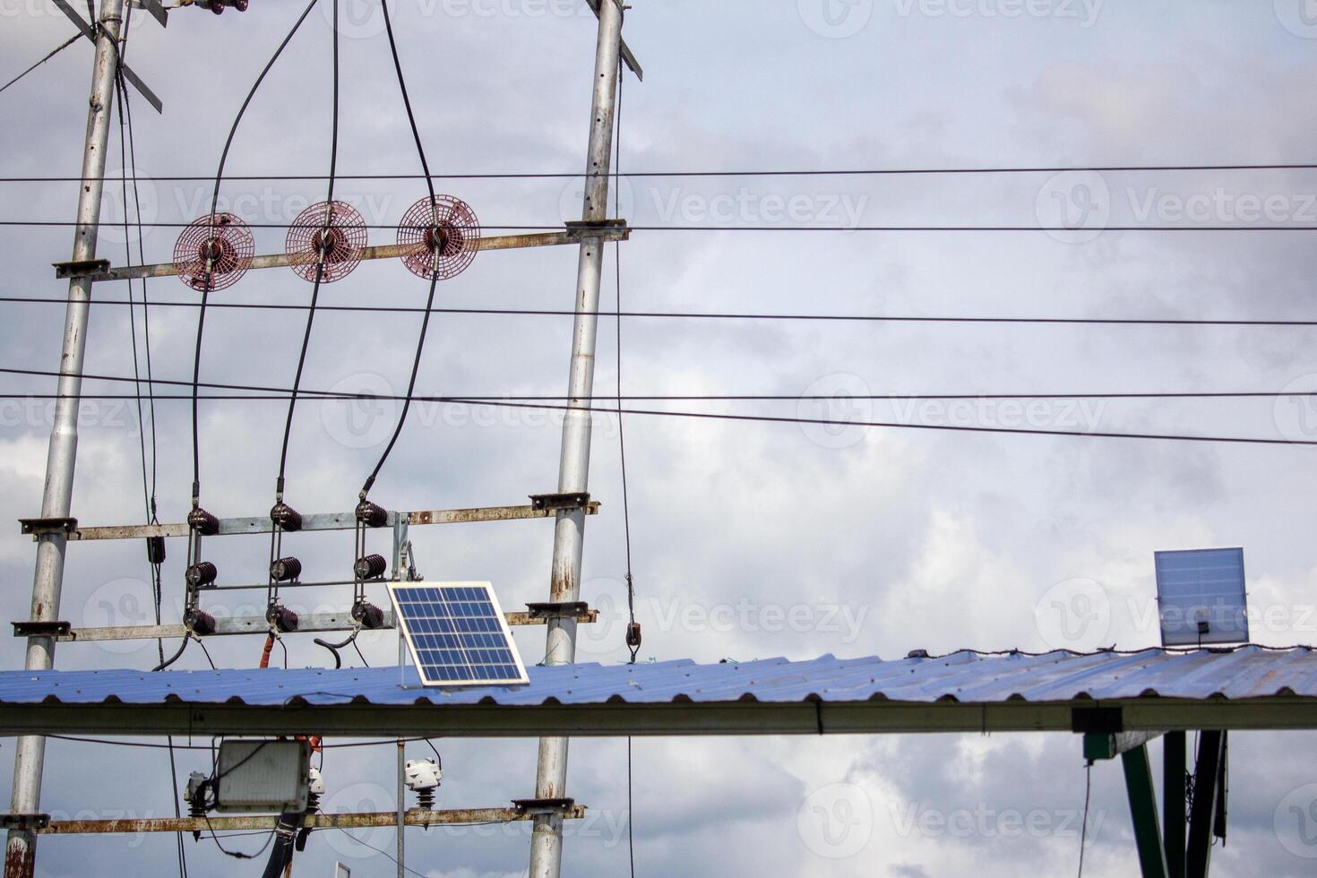 High voltage power lines and solar panels on a structure under a cloudy sky, symbolizing renewable and electrical energy integration photo