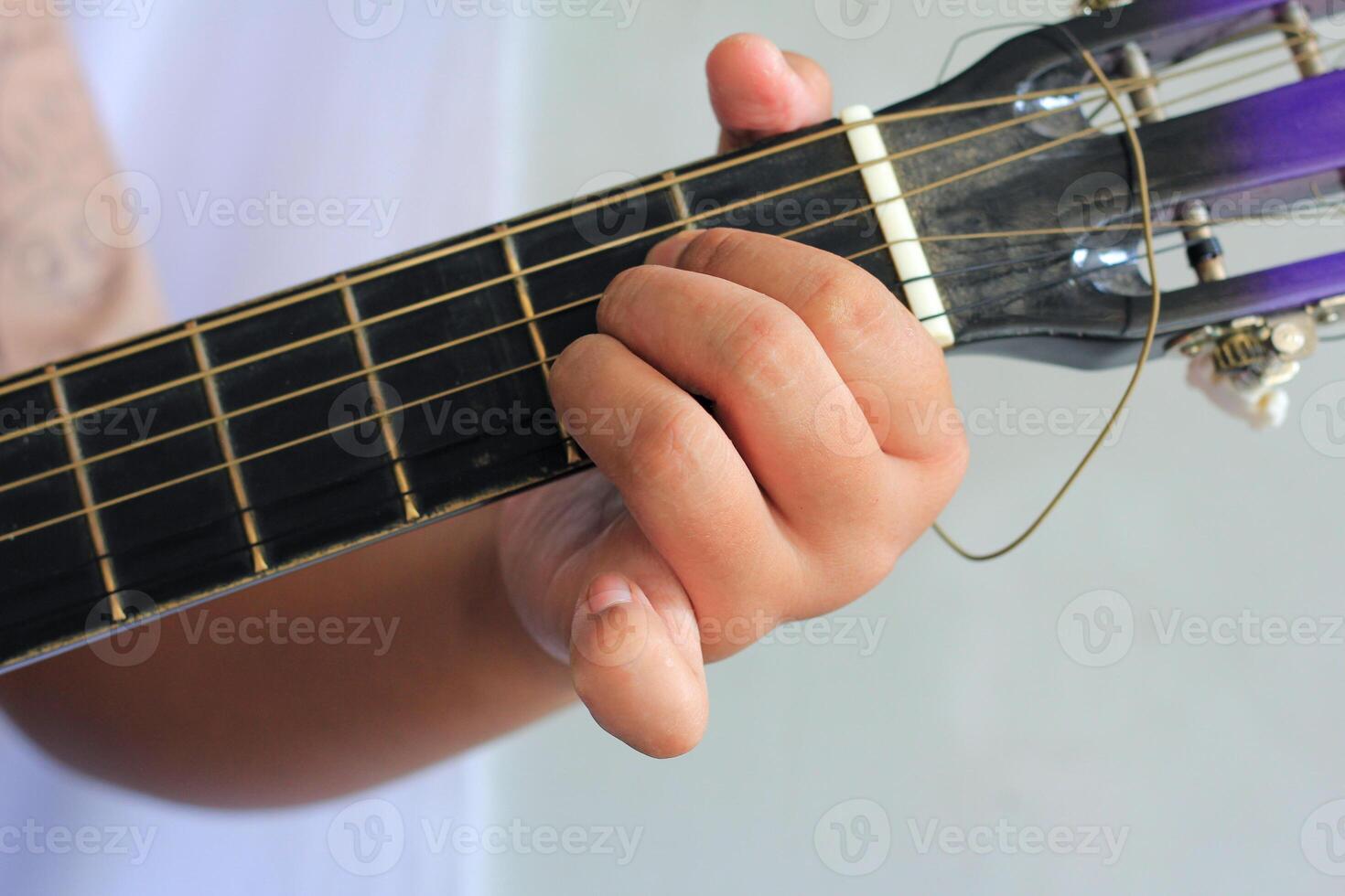 Close-Up of Fingers Pressing Guitar Strings on Fretboard While Playing Music photo