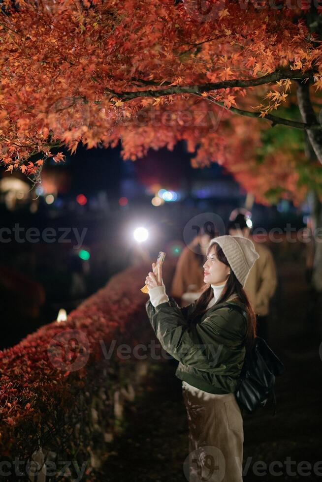 A woman taking a photo of the autumn leaves