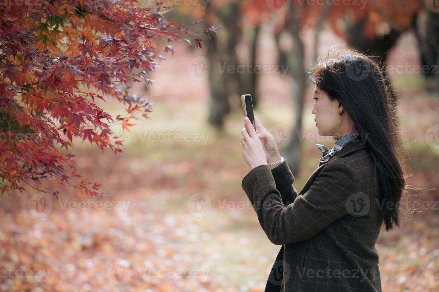 A woman taking a picture of a tree with her phone photo
