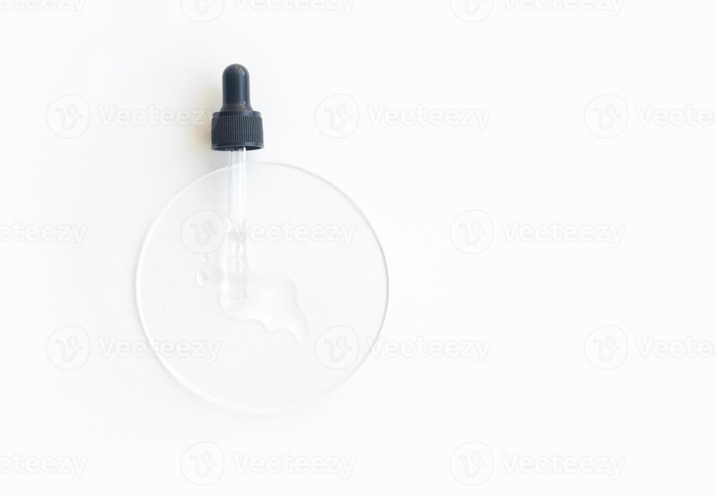 Transparent serum dropper on white surface with clear liquid for skincare and beauty treatments. photo