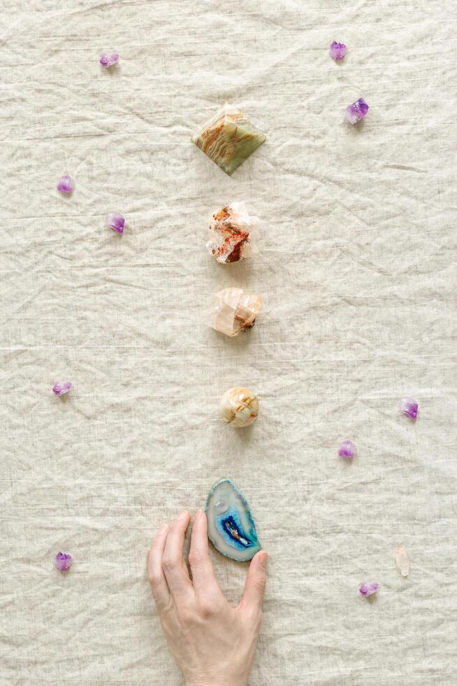 Top view crystal and stone in row, female hand hold one of healing minerals agate, quartz, amethyst, onyx. Stones for crystal therapy. Flat lay semiprecious gems, alternative medicine concept photo