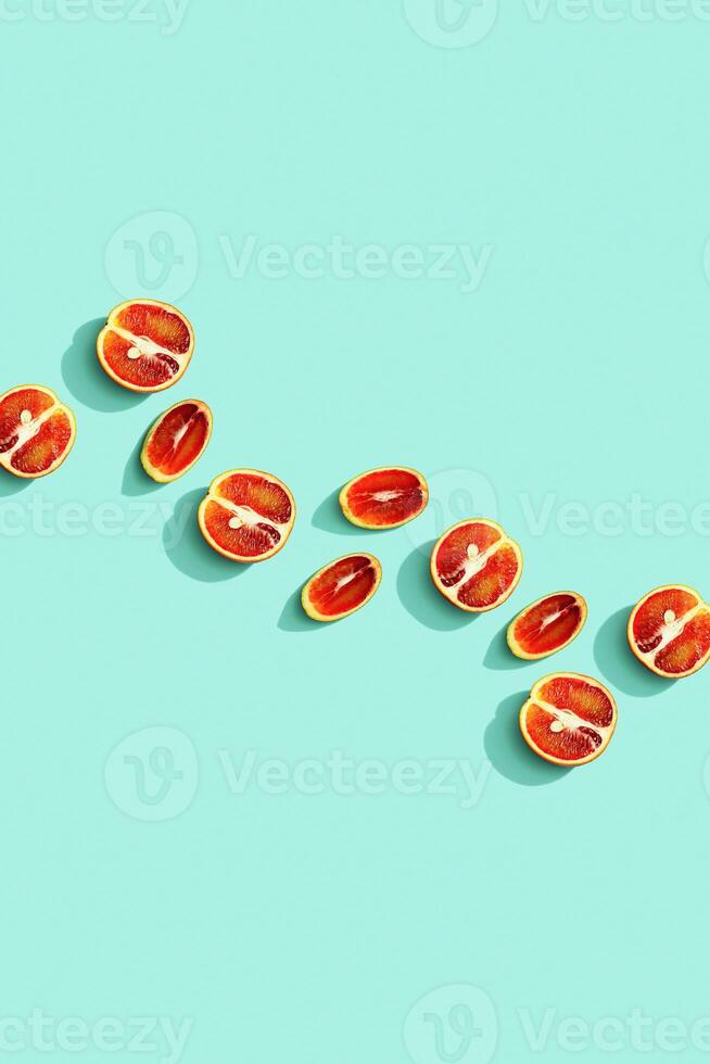 Citrus red orange fruit as creative background, slices of orange with hard shadows at sunlight on pastel mint background with copy space. Healthy fruits food concept. Flat lay, top view photo