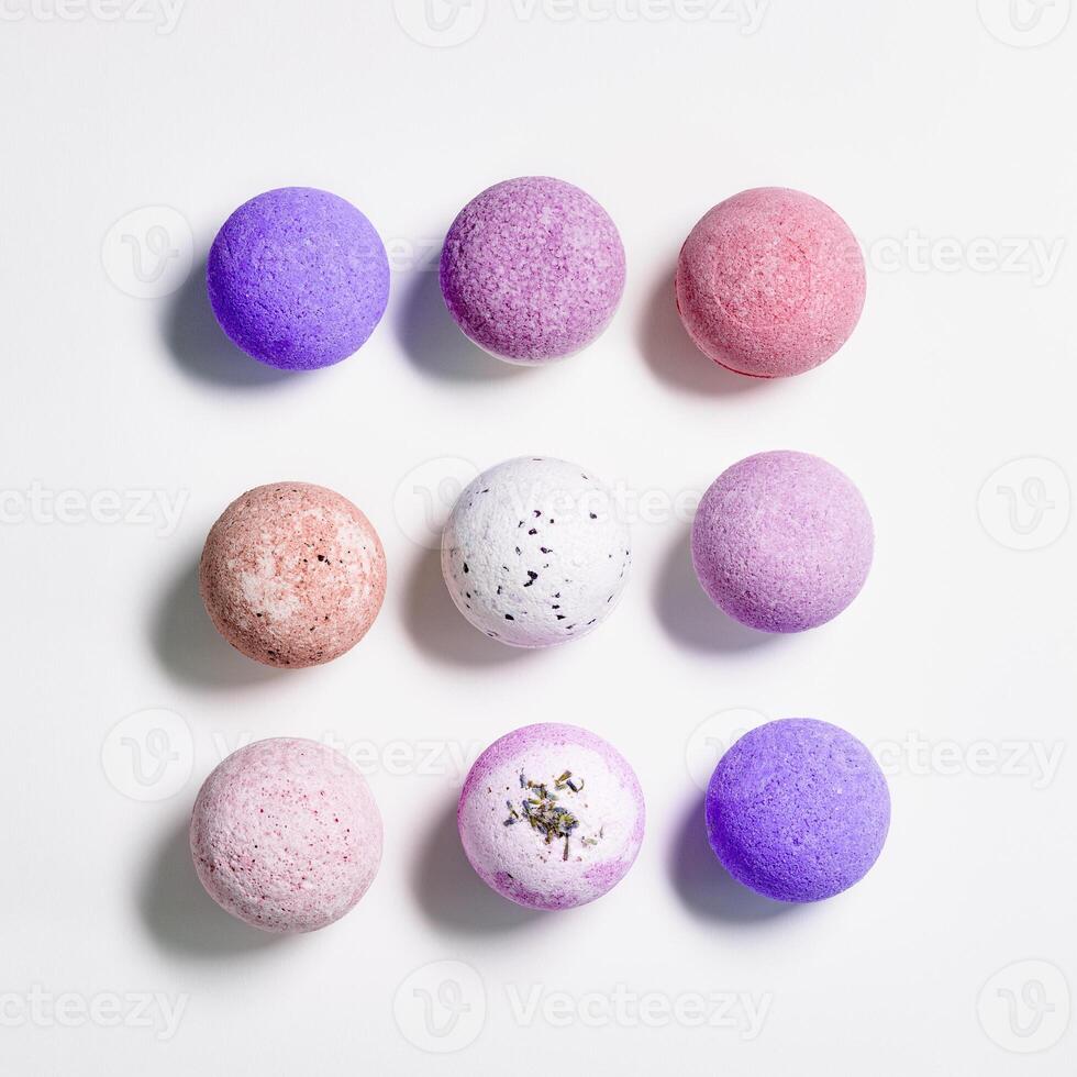 Flat lay composition with bath bomb pink, violet, purple colored on white paper background. Bathing balls with essential oils for relaxation and aromatherapy. Body care natural products photo
