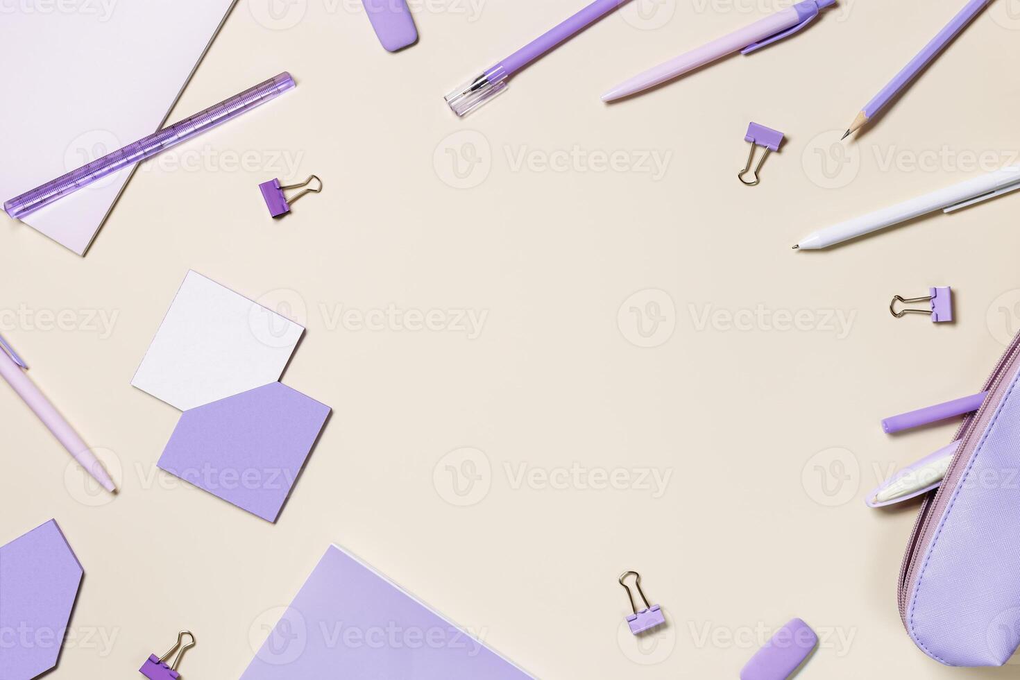 Frame with notebook violet color, pencils, pens, paper clips, pencil case, school stationery flat lay. Back to school concept on beige background, copy space. Office supplies on table photo