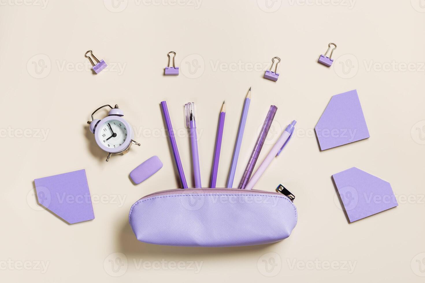 Office supplies very peri color, pencils, pens, paper clips, erasers fly from pencil case. School stationery flat lay on table. Back to school pattern on beige background. Copy space photo
