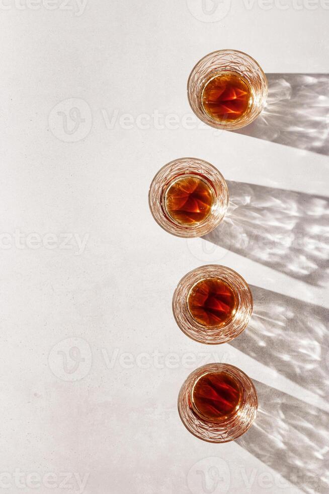 Crystal Whiskey Glasses with shadows at sunlight on beige textured background, minimal aesthetic flat lay shiny glasses, sun glare, stong alcohol drink concept, summer still life photo
