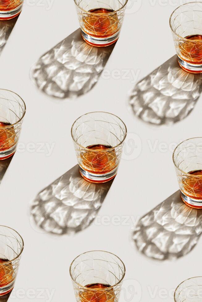 Transparent Glasses with alcohol drinks, shadow at sunlight on beige concrete table, minimal style, creative aesthetic pattern shiny glass sparkling at natural light, summer strong drink, above view photo