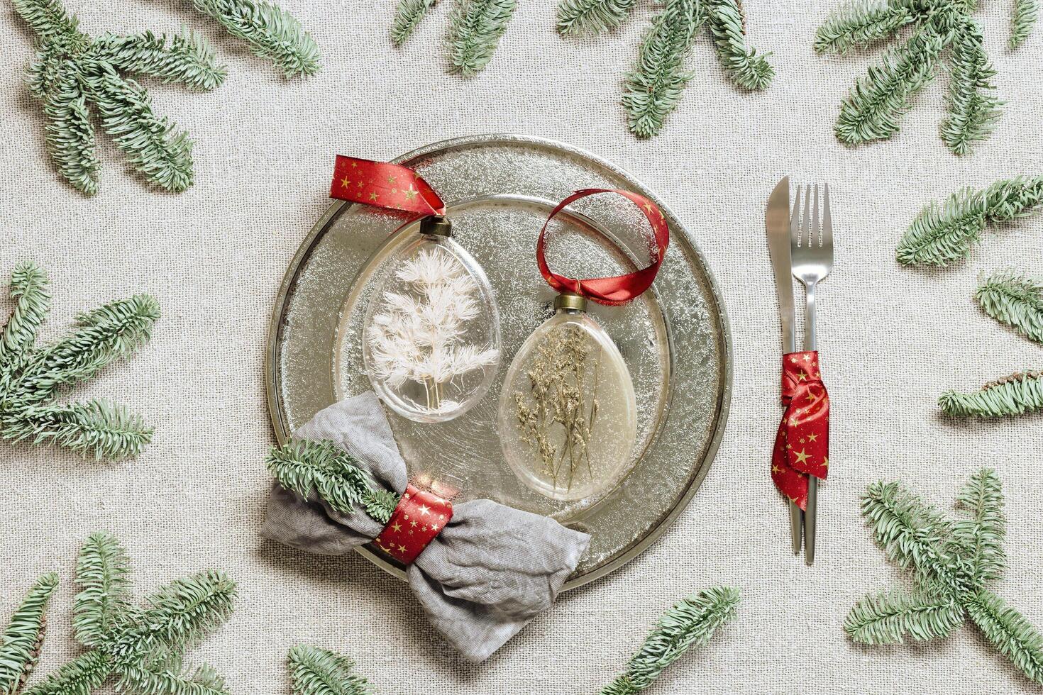 Tableware for Christmas or Xmas festive dinner, linen napkin on plate, red wine glass, bottle of wine on rustic tablecloth. Pattern with New Year holiday cutlery, glass Christmas ornament photo
