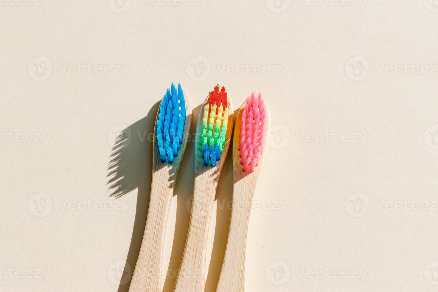 Eco-friendly wood toothbrushes with soft colorful bristles at sunlight on beige background. Minimal design photo, sustainable hygiene concept, Zero waste lifestyle, eco-conscious living, hard shadow photo