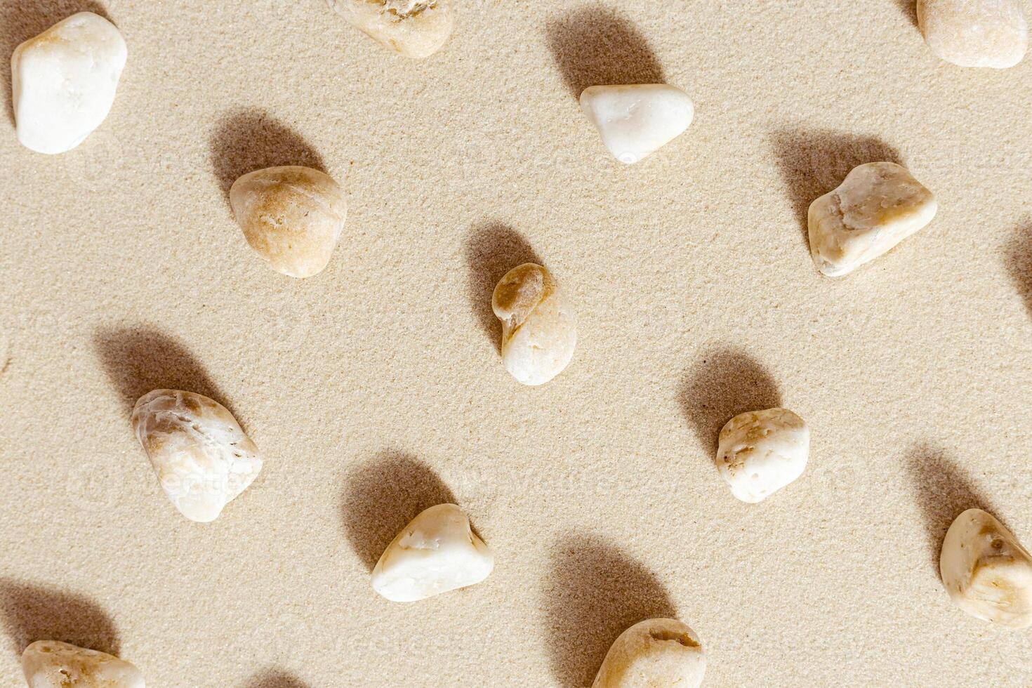 Pattern with pebble sea stones on fine sand. Natural stone neutral beige yellow color, monochrome tones. Summer minimal design background photo