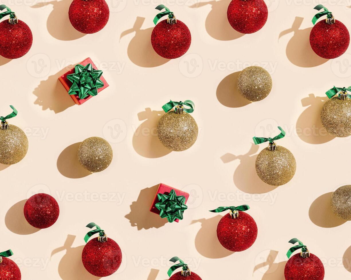 New Year holiday pattern with shiny red and golden Christmas balls and small gift box or present on pale pink background, minimal geometric layuot photo