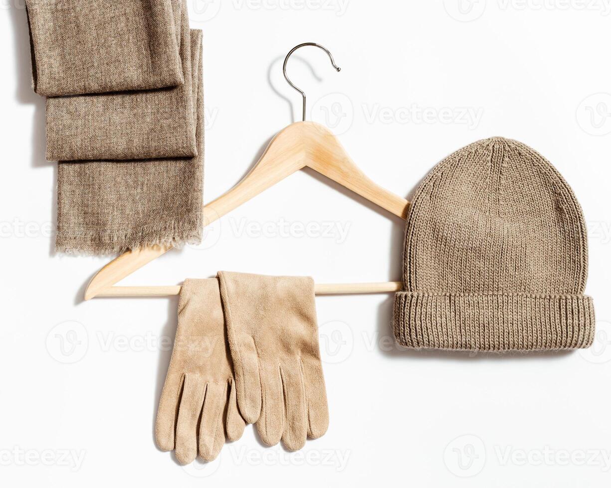 Knitted hat, scarf and suede gloves on clothes hanger. Fashion warm clothing concept photo