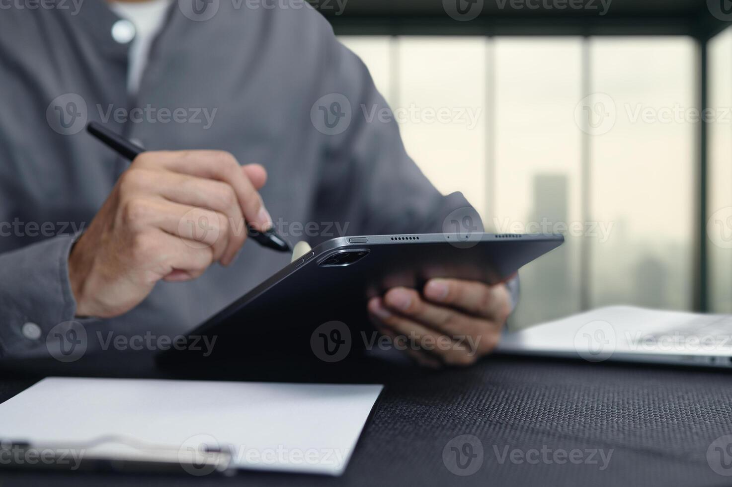 Man Using Tablet with Stylus in Modern Workspace Setup photo