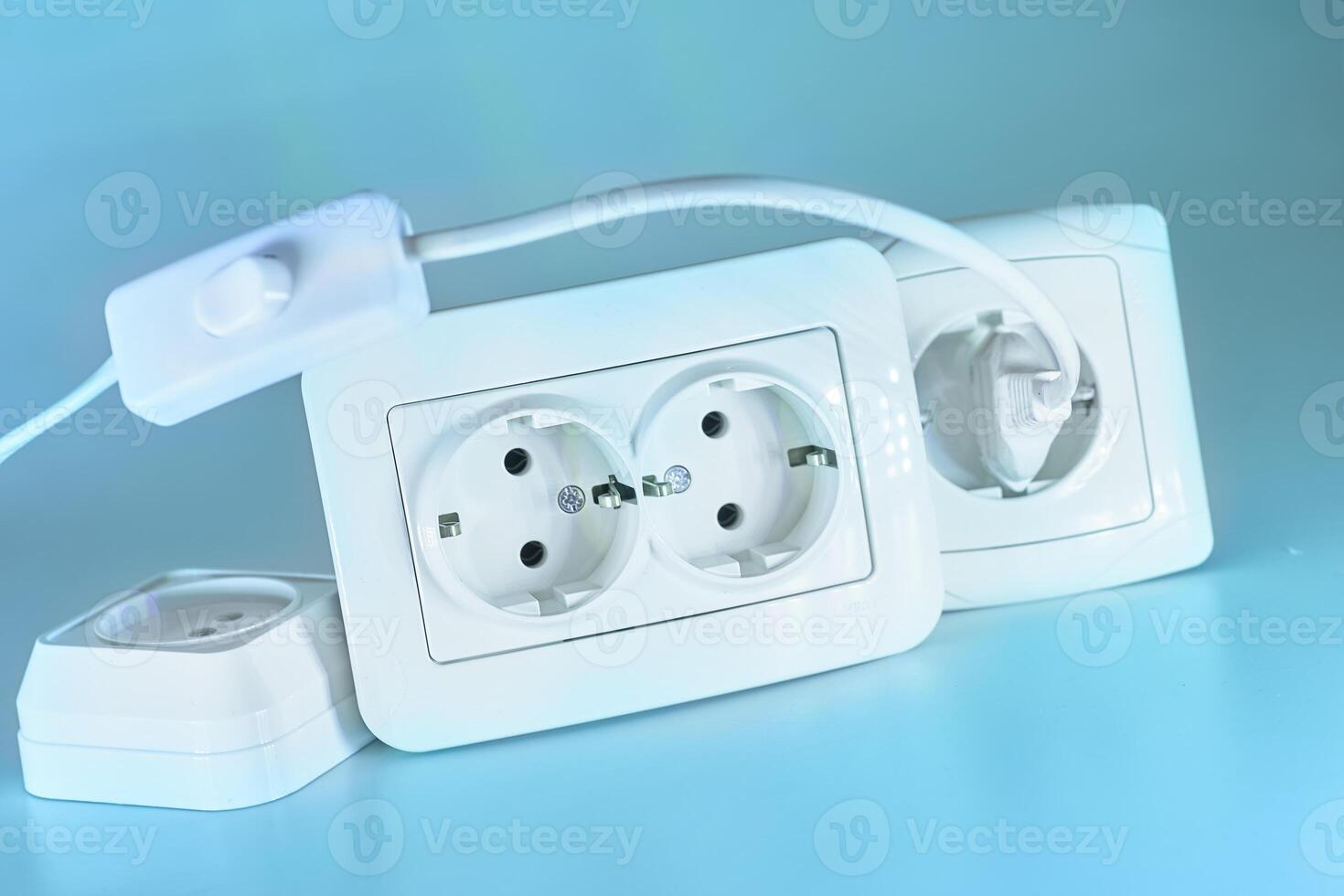 Three electrical sockets for connecting devices and a switch on blue photo