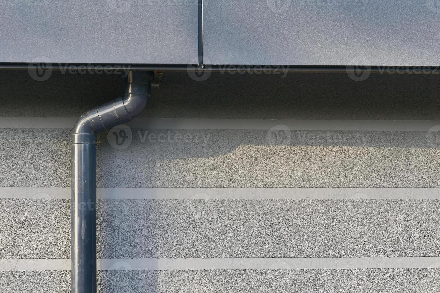 Rain drainage runoff.New plastic drain pipe on a gray plastered wall photo