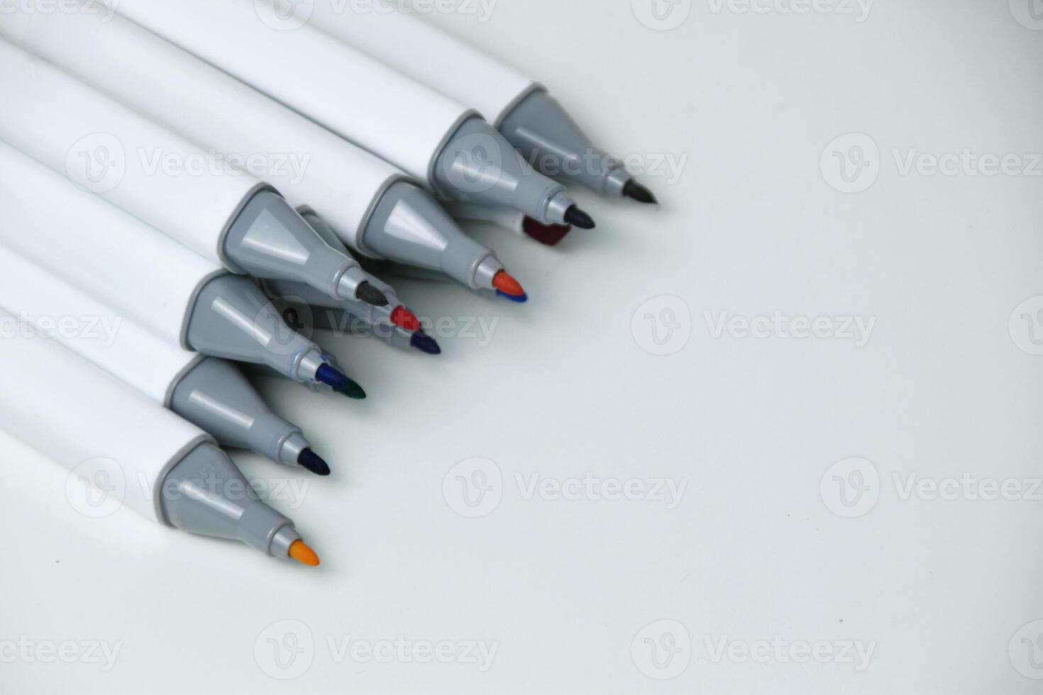 Open markers arranged neatly on white surface photo