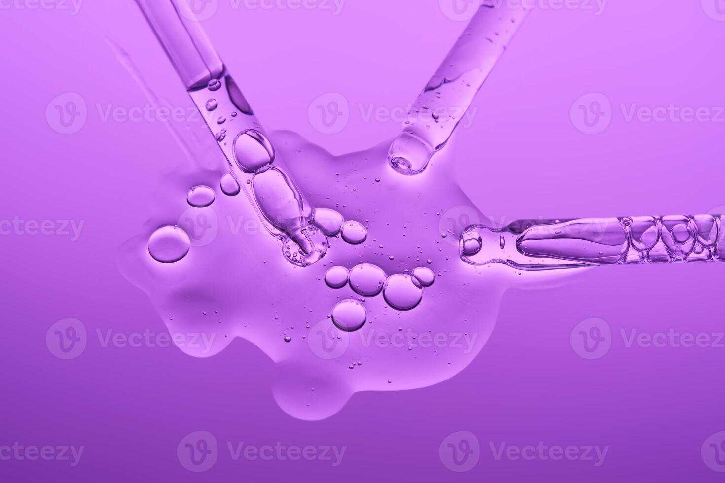 Transparent serum and several cosmetic pipettes on a lilac background. The texture. photo