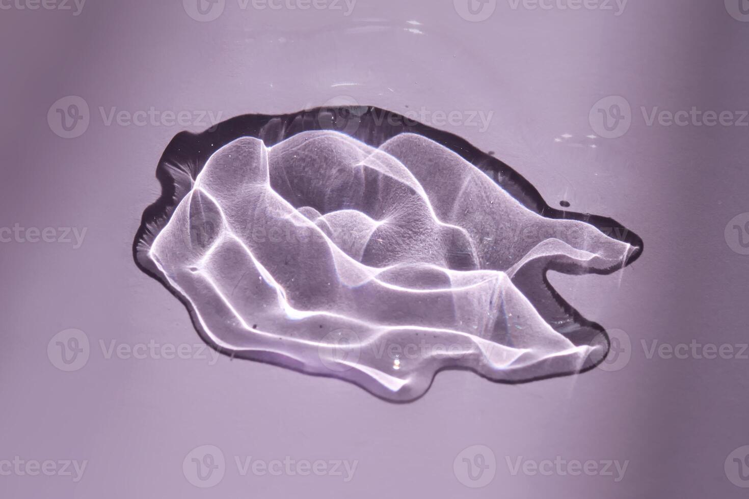 A drop of oil serum on a purple background with beautiful highlights. photo