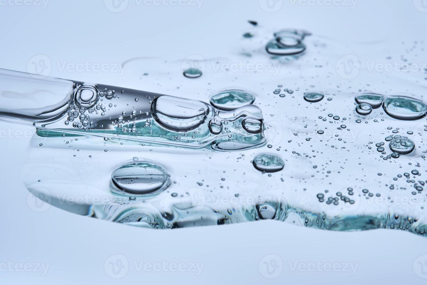 A puddle of transparent serum with microneedles on a blue background. photo