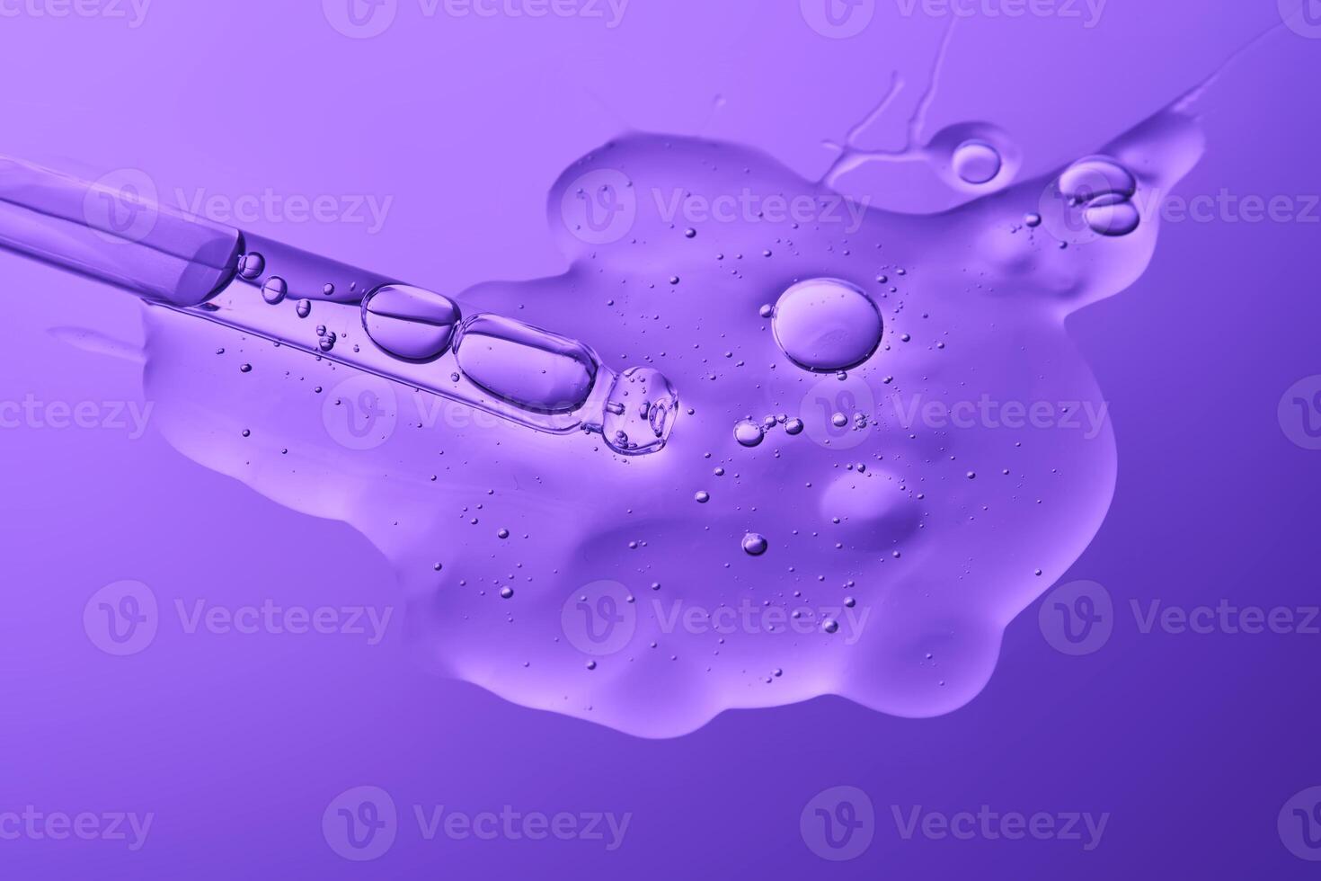 The texture of the serum and the cosmetic pipette on a purple background. photo