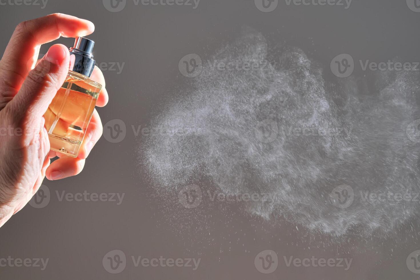 The hand sprays the fragrance for the house from a transparent rounded bottle. An air freshener. photo