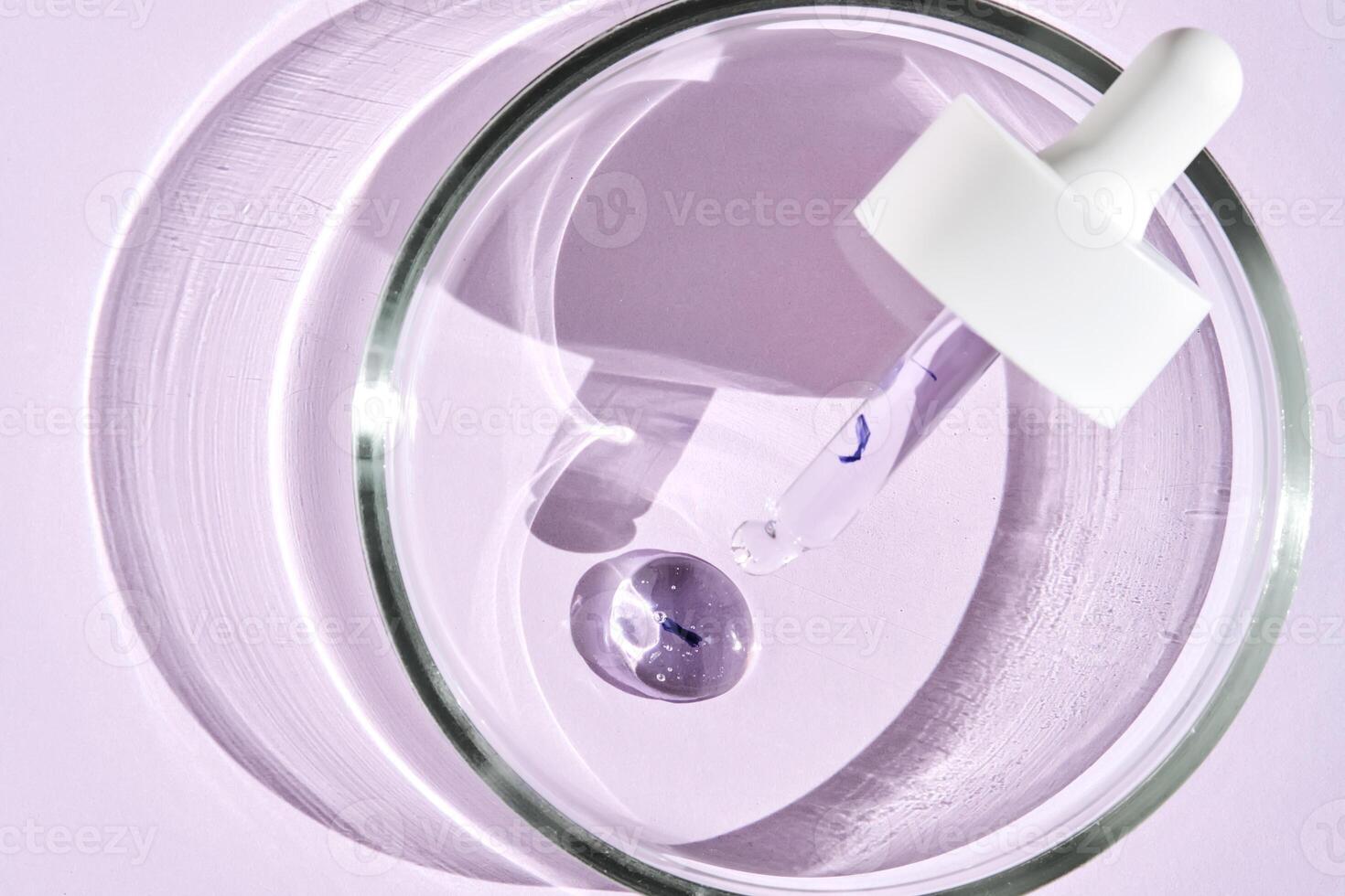 The texture of the serum and a cosmetic pipette in a petri dish on a purple background. photo