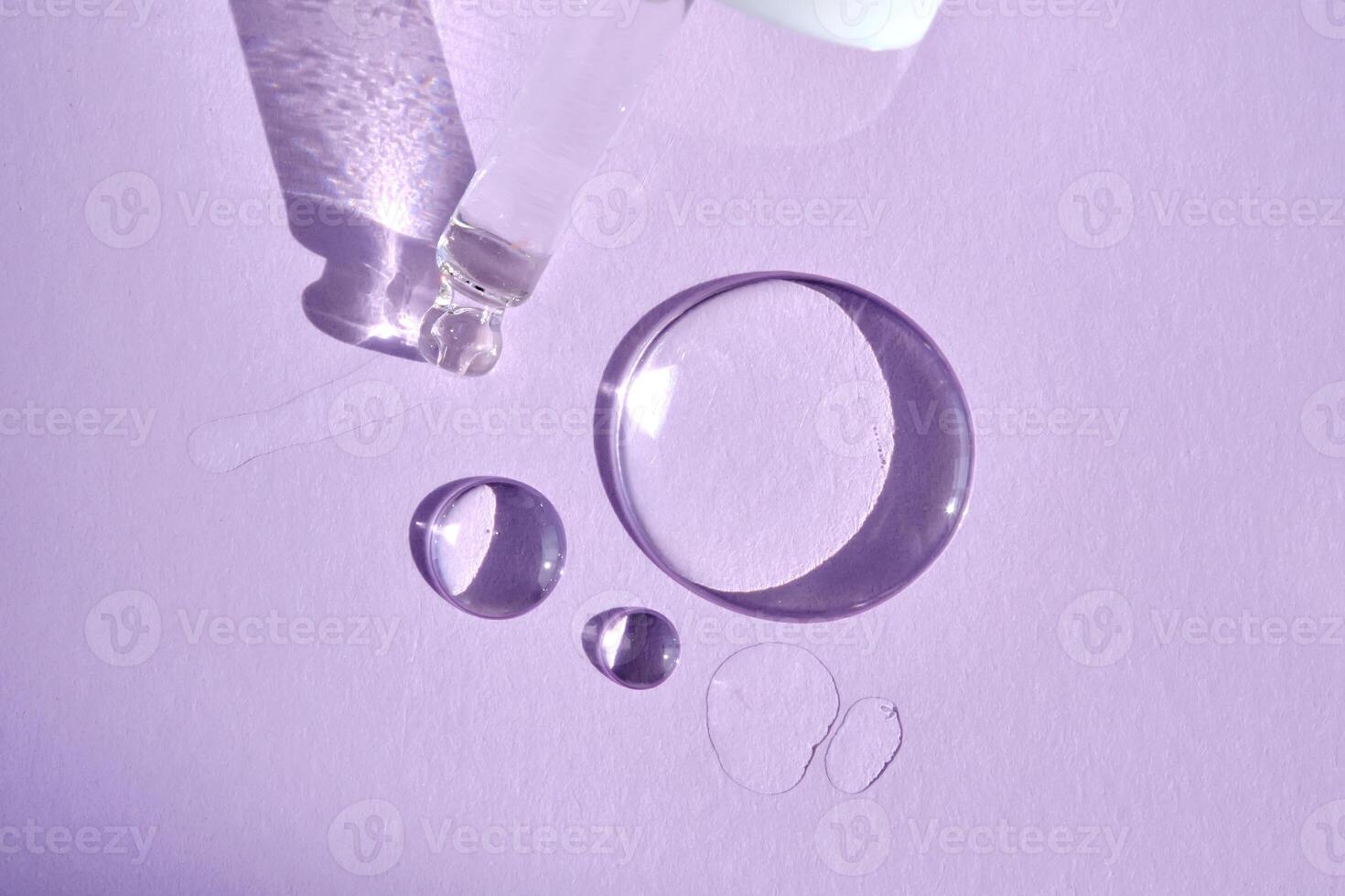 A drop of serum with a pipette on a purple background. photo