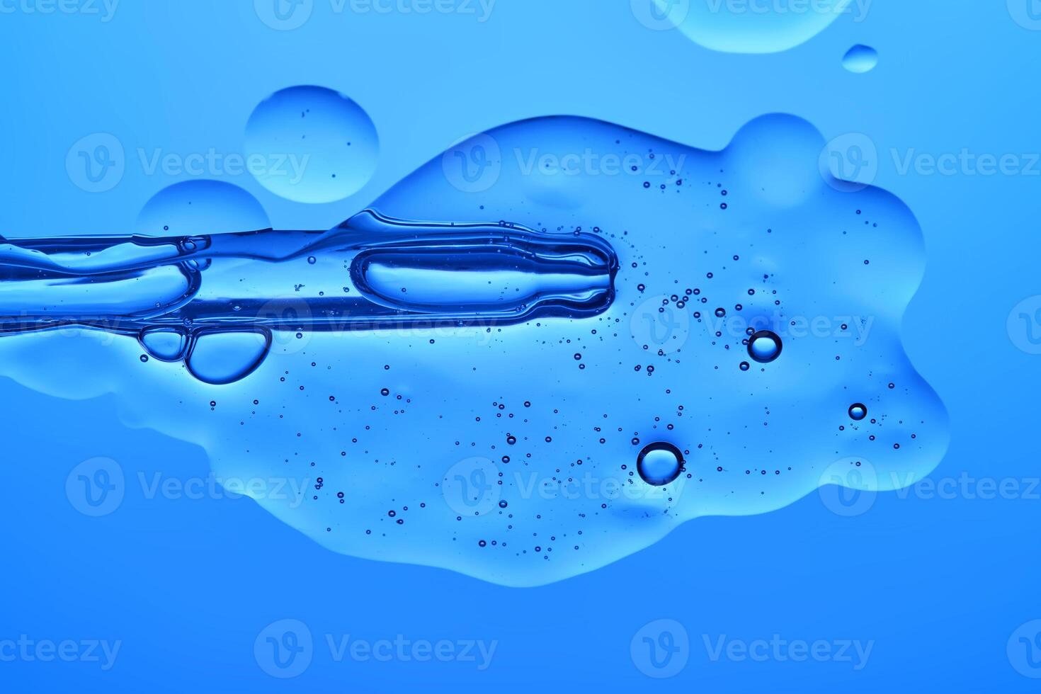 A dropper with a transparent serum texture on a blue background. photo
