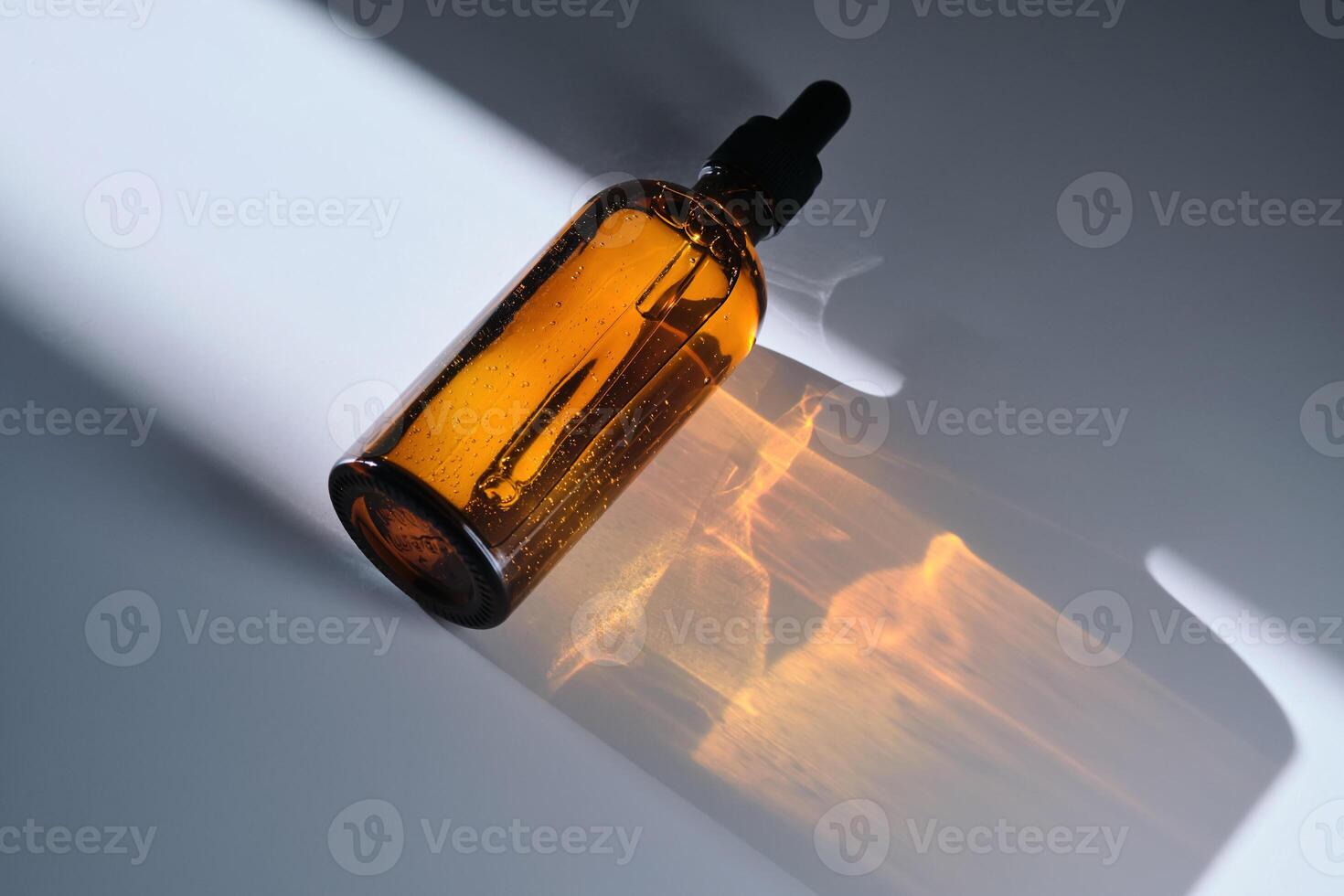 A bottle of serum made of brown glass on a white background with stripe of light. photo