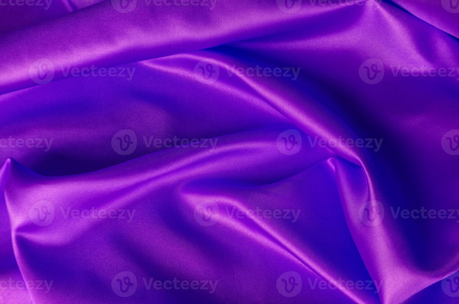 Top view of shiny maroon satin cloth with radiant surface highlights and fine woven texture in natural folds photo