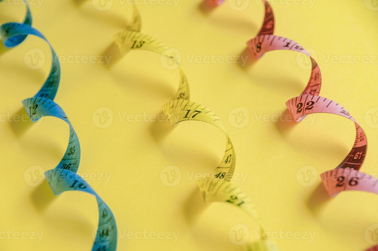 curled blue measuring tape on vibrant yellow surface represents accuracy and creativity photo