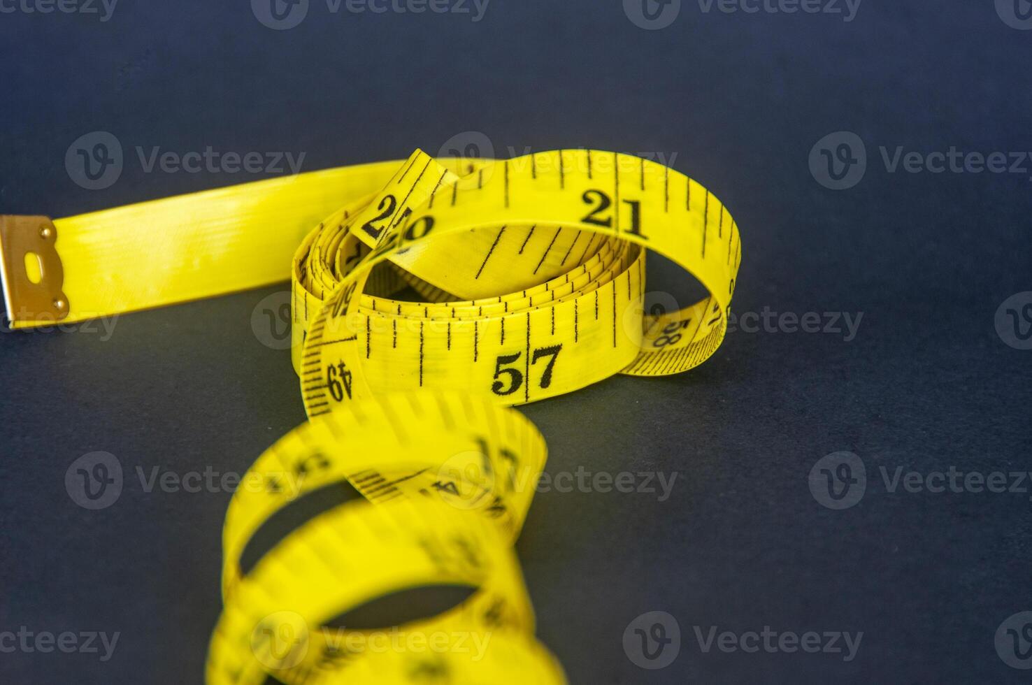 Close up view of yellow measure tape on dark background with customizable space for text. Dieting and copy space concept photo