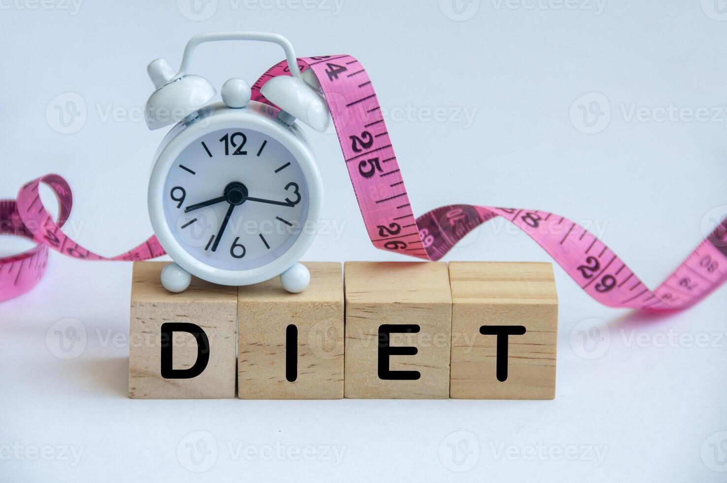 Diet text on wooden cube with alarm clock and measuring tape background photo