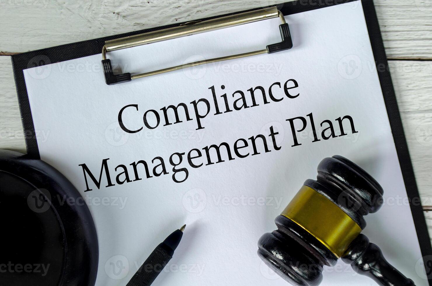 Top view of Compliance Management Plan text on white paper clipboard with gavel photo