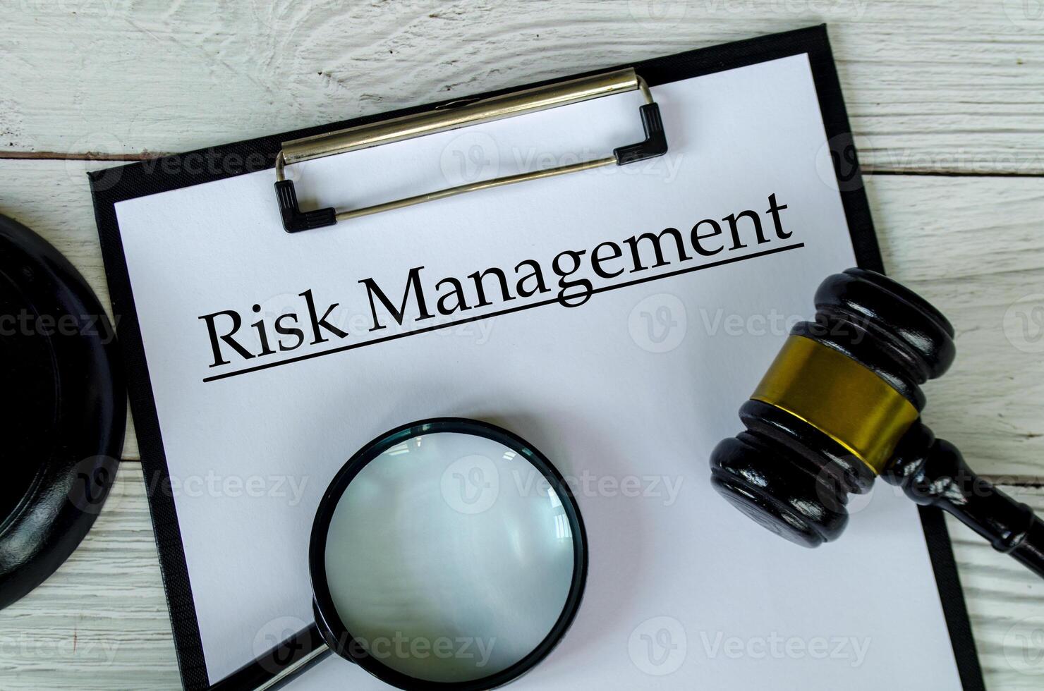 Top view of Risk management text on white paper clipboard with gavel and magnifying glass photo