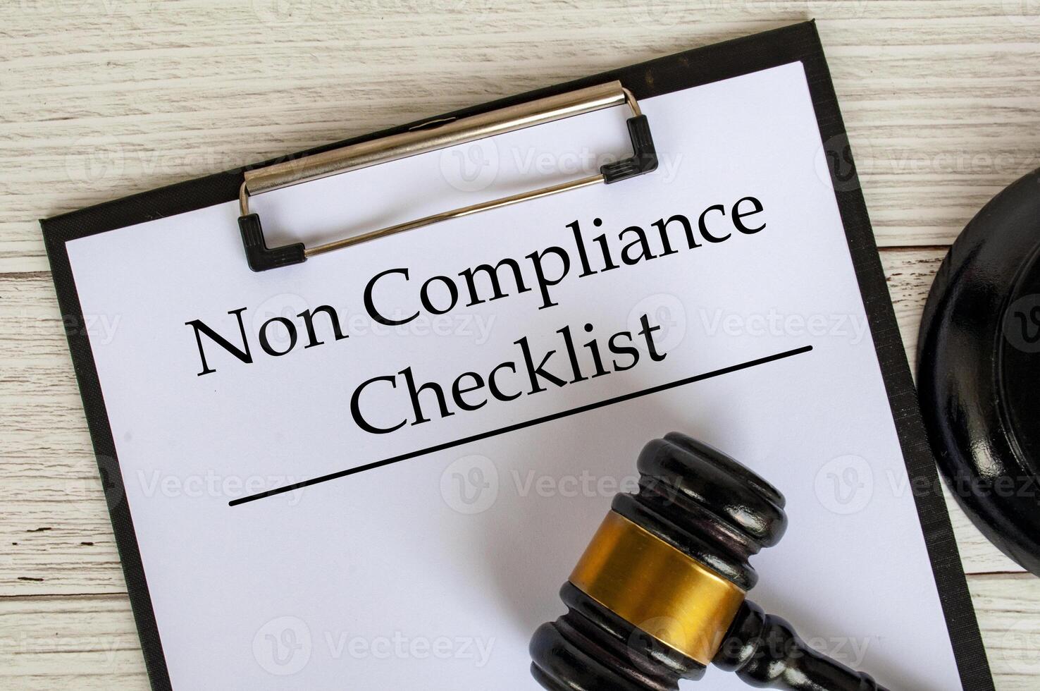 Top view of Non Compliance Checklist text on clipboard with gavel on top. Compliance concept photo