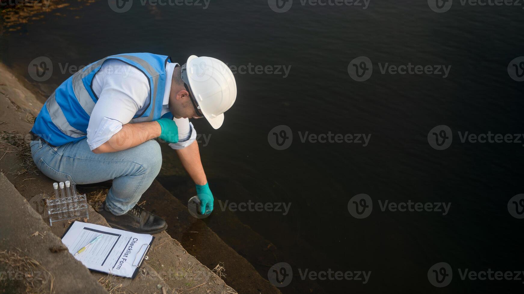 A water resource worker is collecting water samples in a large reservoir. photo