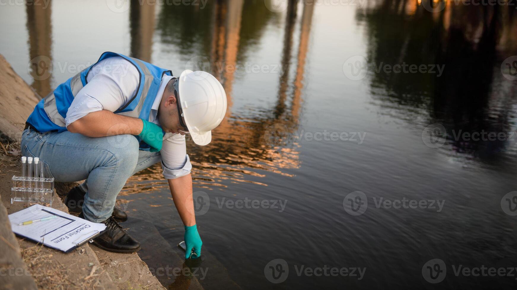 the water resource worker is collecting water samples in a large reservoir photo