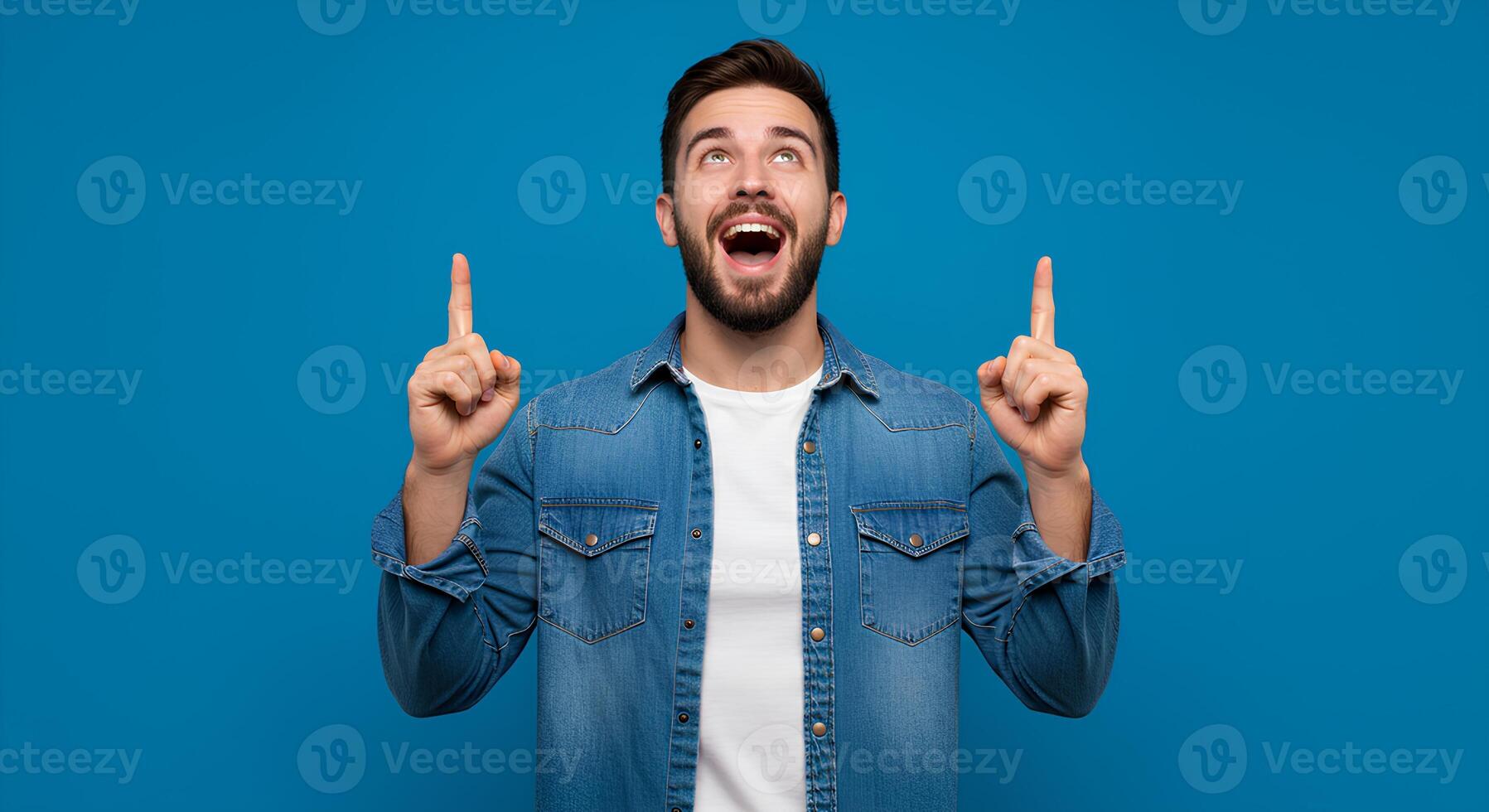 Enthusiastic Man Pointing Upward Against a Blue Background photo