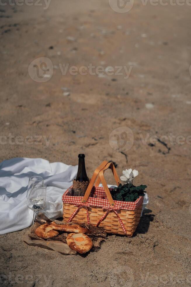 Aesthetic Outdoor Dining and Stylish beach picnic with wine basket pastries and flowers in soft light photo