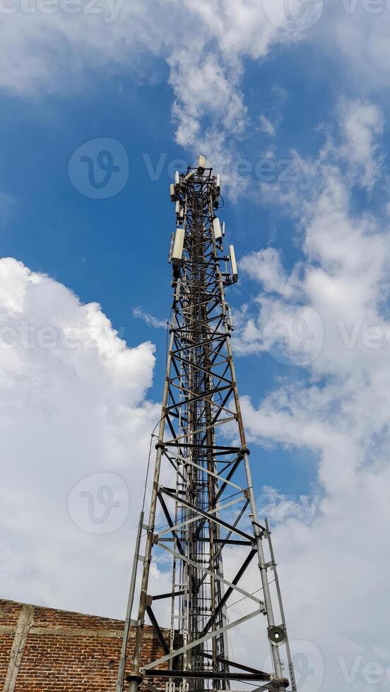 Communication tower against clear blue sky with white fluffy clouds wireless connectivity backdrop photo