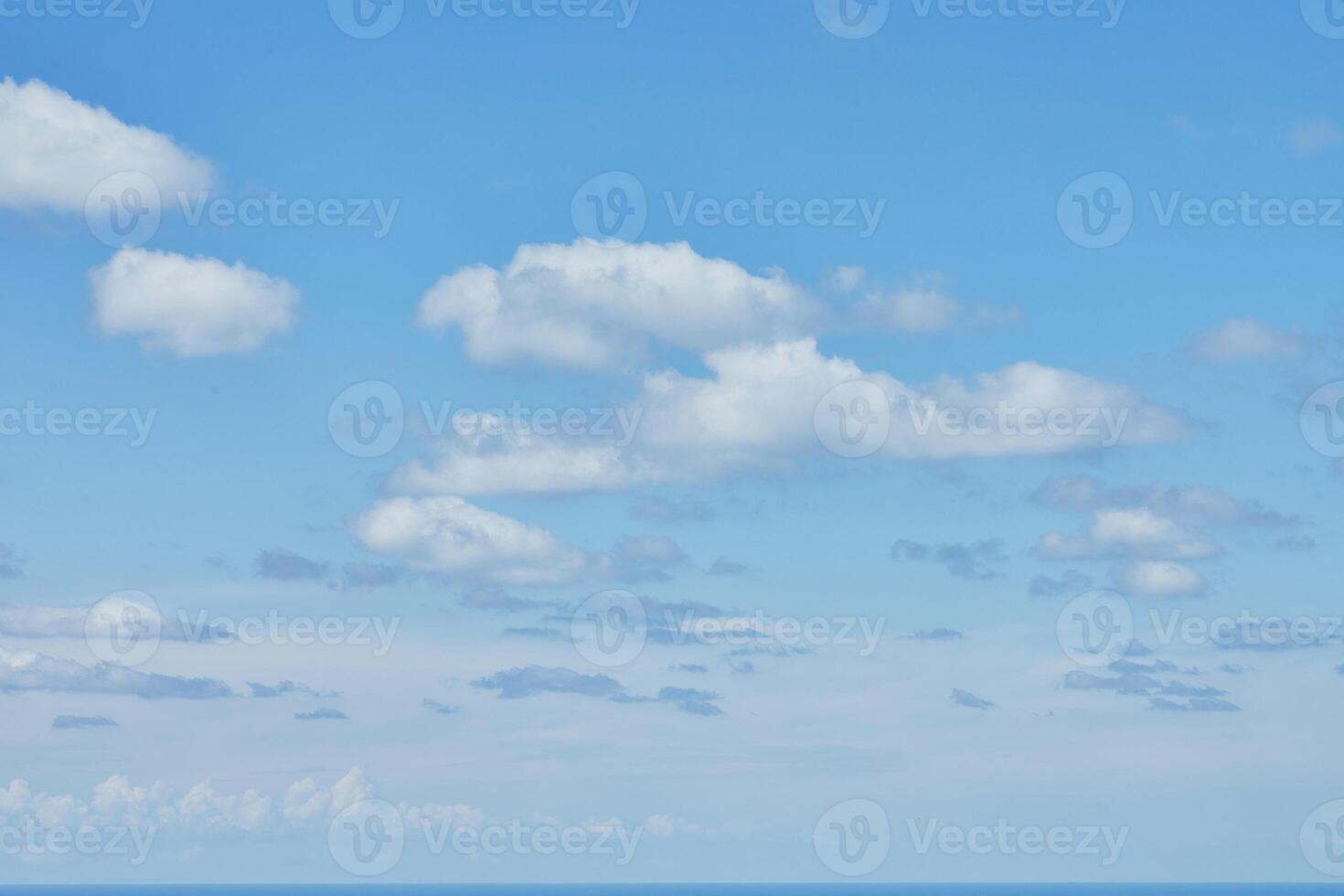 A bright blue sky dotted with fluffy white clouds over the horizon, evoking feelings of peace and openness photo